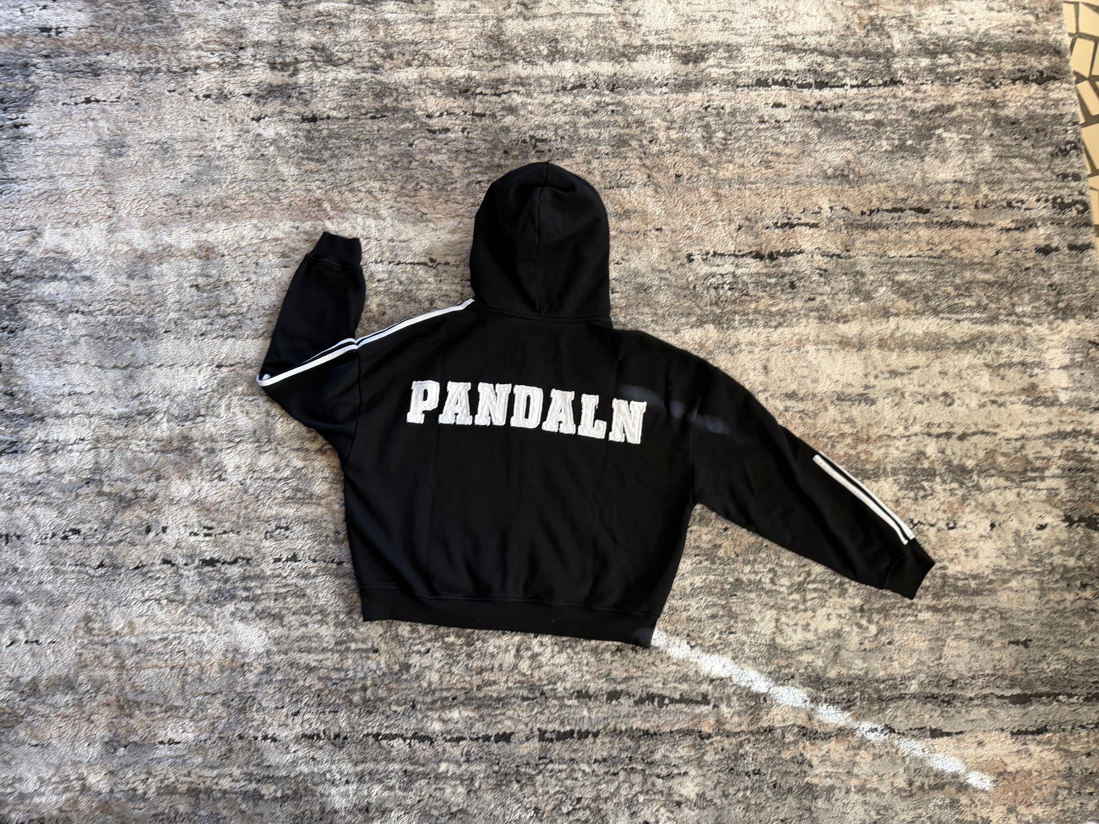 Black hoodie with 'PANDALN' text on a textured surface